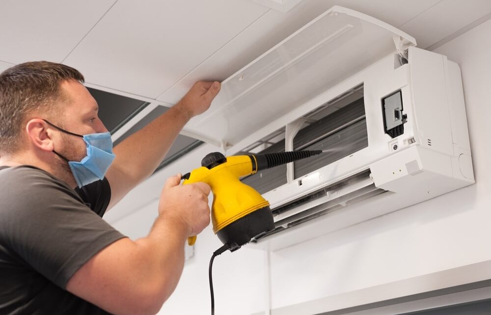 Personne nettoyant avec soin le filtre à air d'une unité intérieure de climatiseur.
